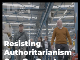 Visual Description: Several professionally dressed middle-aged white people walk down the floor of a brightly lit factory. Text is overlaid in white that reads Resisting authoritarianism one co-op at a time. The Laura Flanders Show logo appears in the top left corner in white.