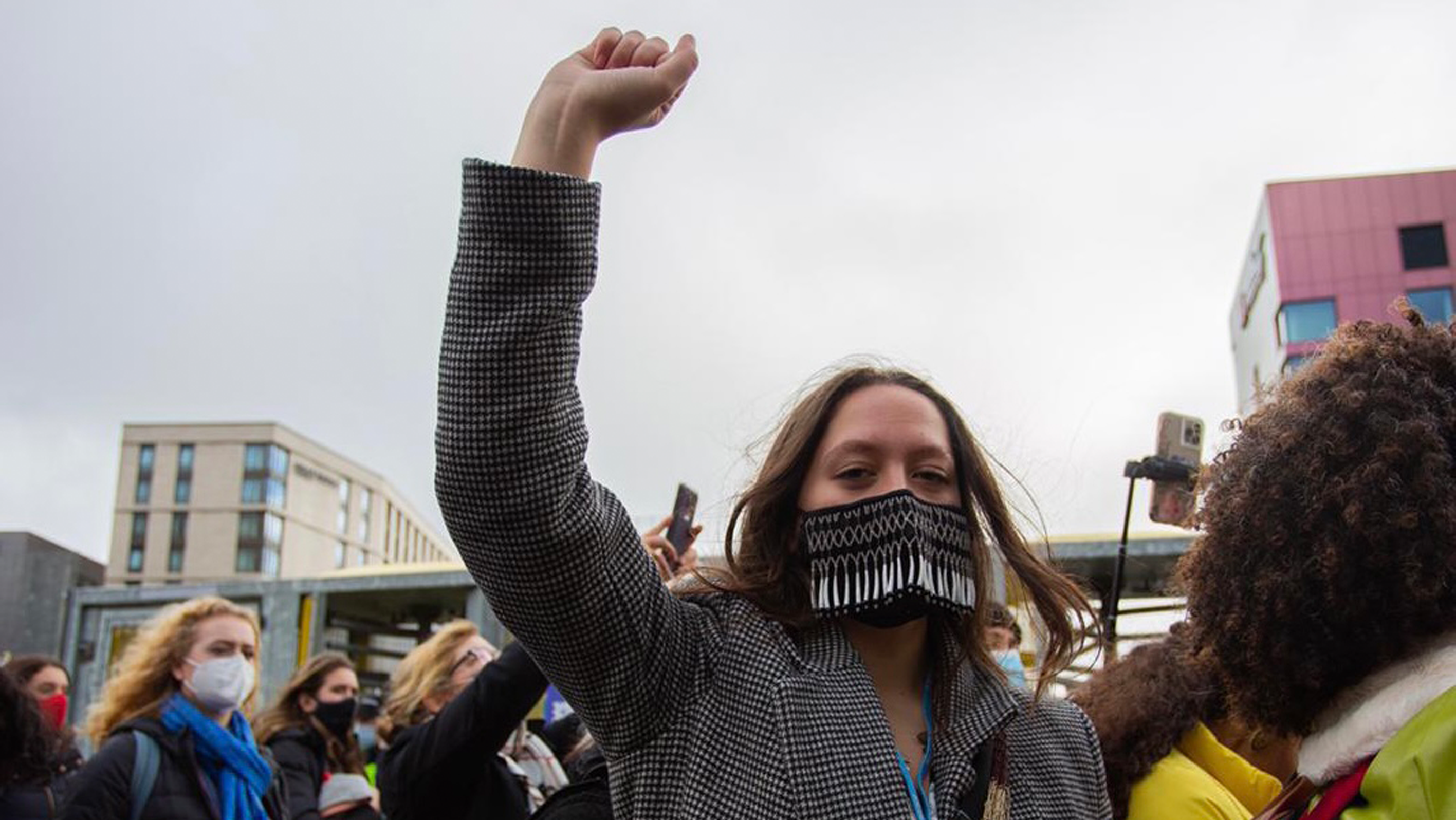 At COP26, Te Maia Wiki raises her fist among a group of activists.